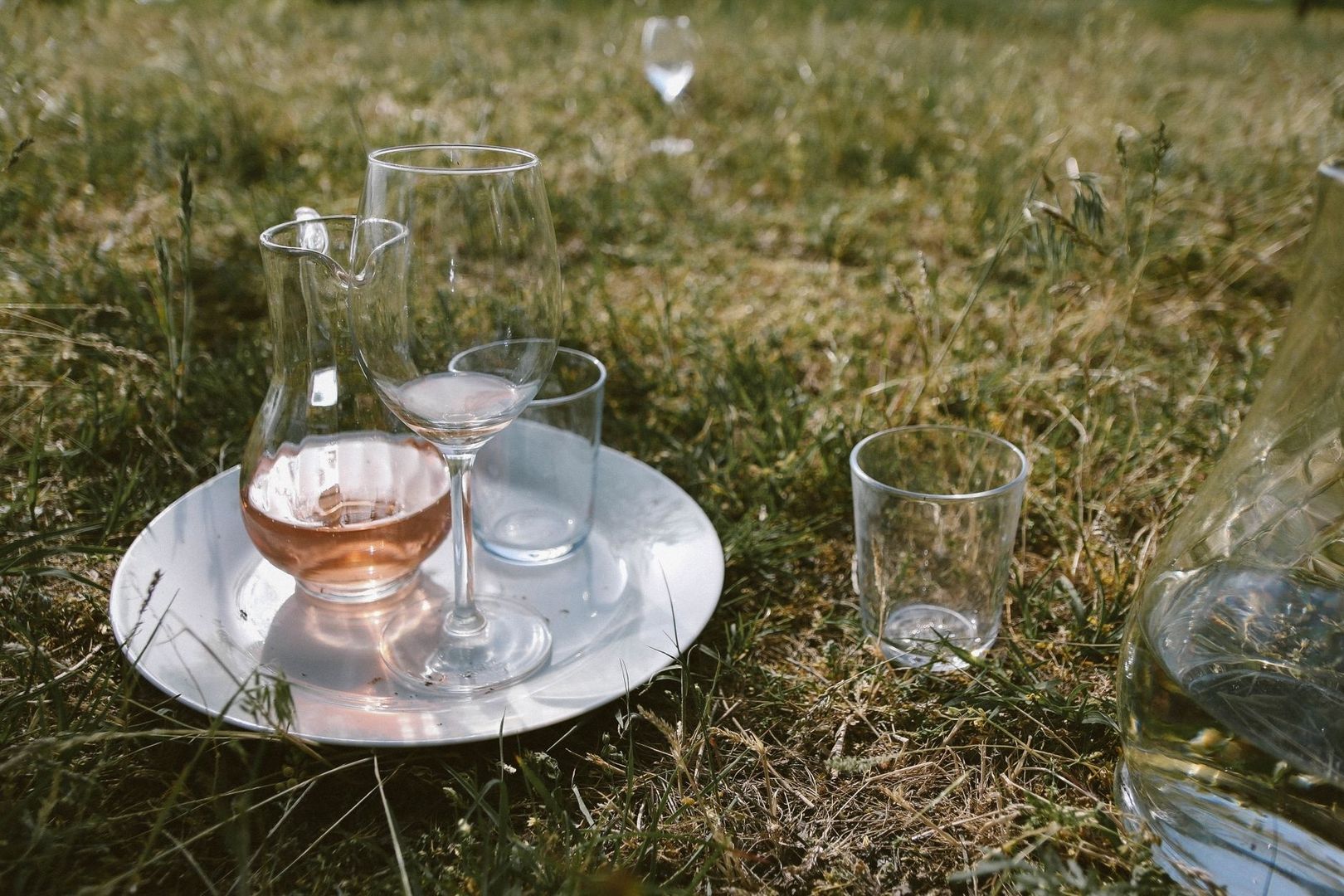 Gläser mit roséfarbenem, leicht trübem Wein auf einer Wiese