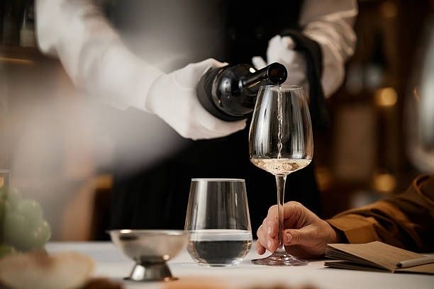 Eine Servicekraft schenkt Wein in ein Glas am gedeckten Tisch ein