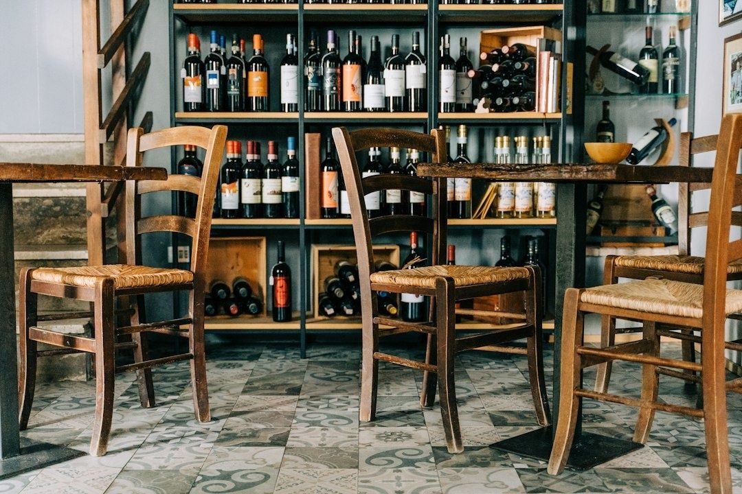Gemütliche Weinbar mit Holztischen, Stühlen und Weinregalen im Hintergrund